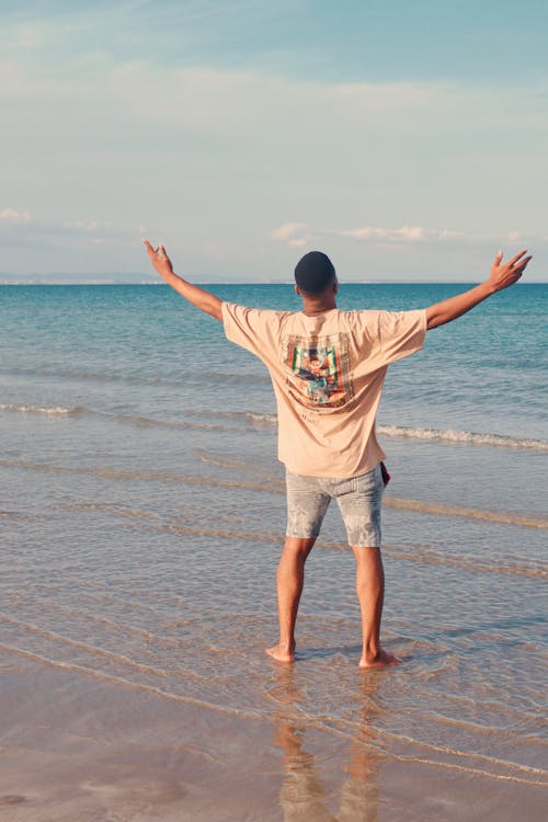 Man standing with arms open at beach during sunset - representing the freedom of recurring passive income